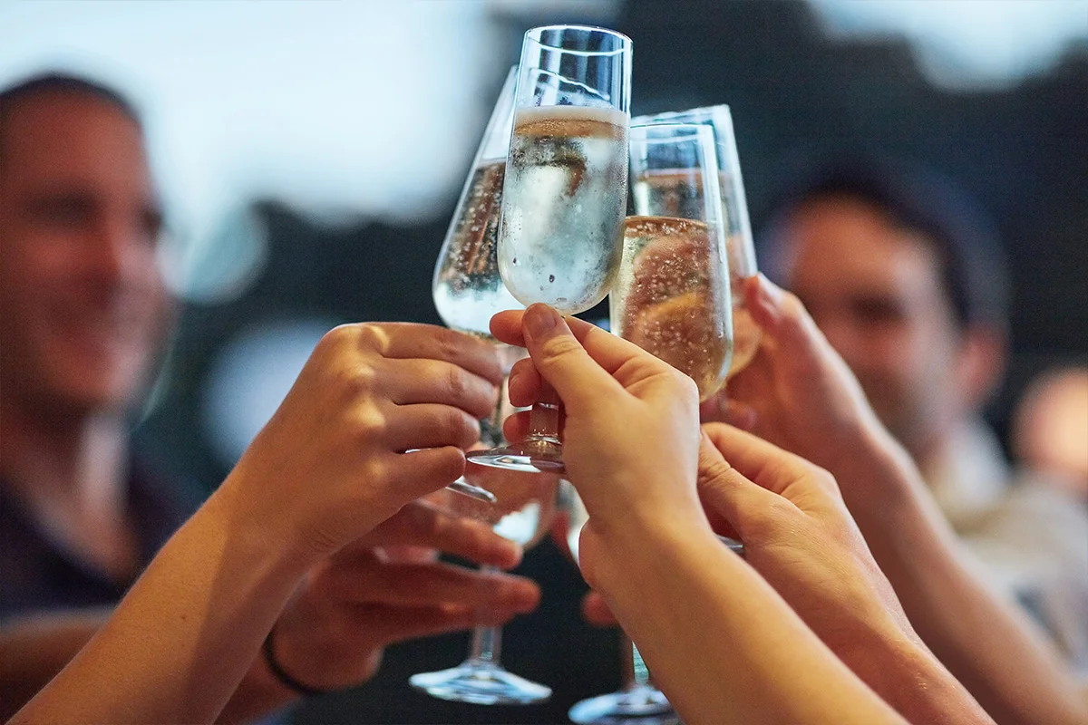 Friends clinking glasses of Champagne in celebration, highlighting Wine Rack’s Christmas drinks deals near you