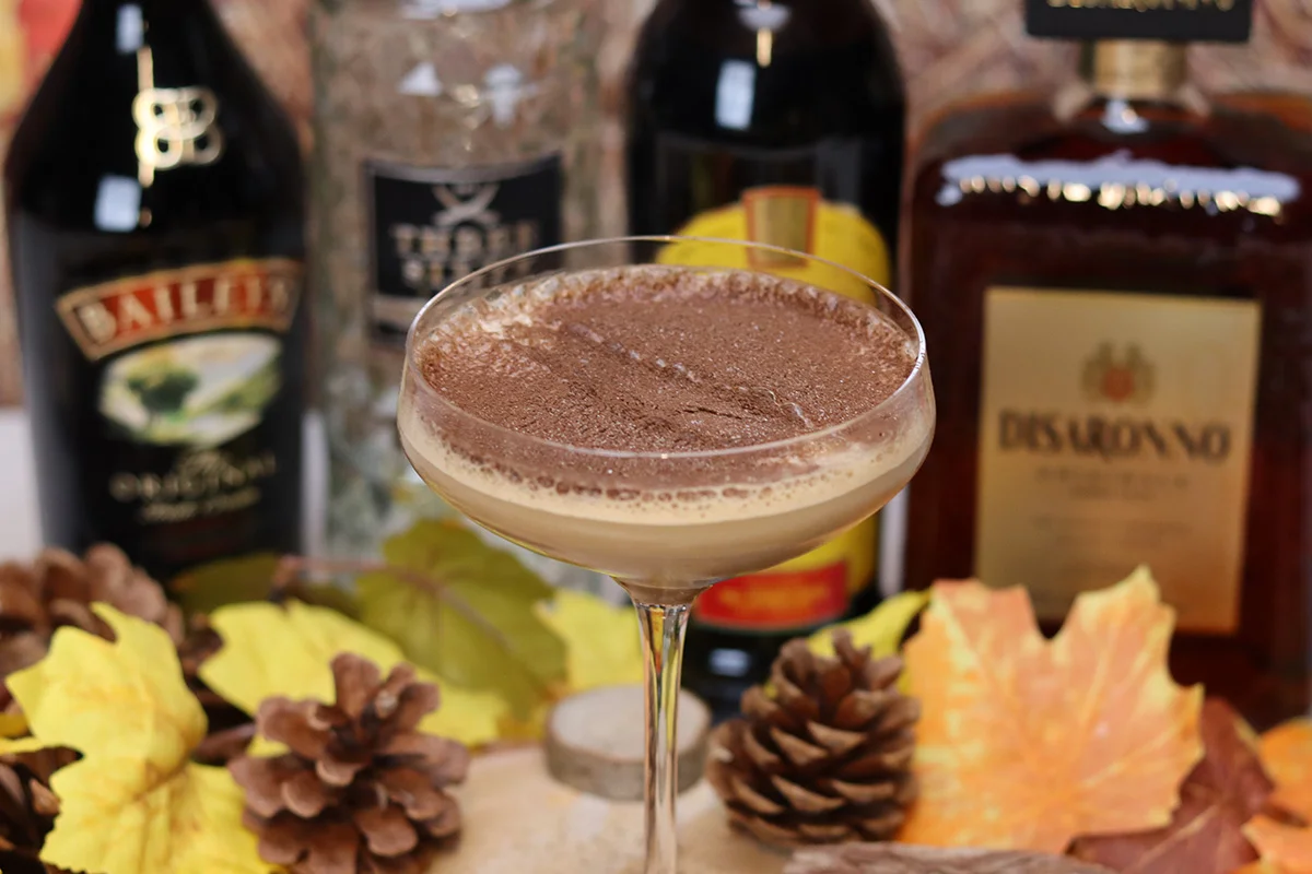 Tiramisu Martini cocktail dusted with cocoa, surrounded by festive pinecones and Baileys bottles, part of Wine Rack’s Christmas drinks deals near you