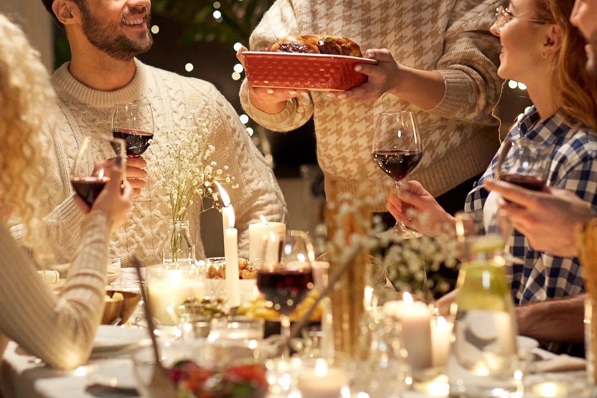 Friends enjoying a festive dinner with wine and candlelight, celebrating together with Wine Rack’s Christmas drinks deals near you