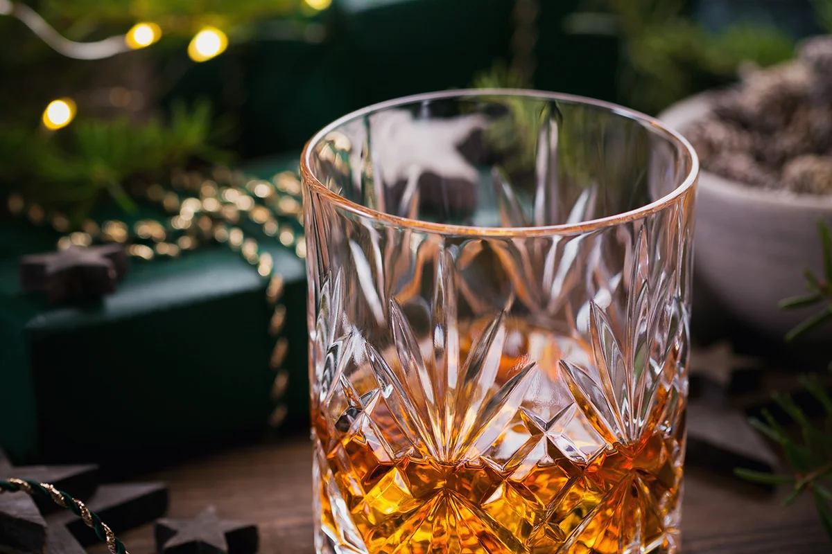 A crystal glass of whisky surrounded by festive decorations, symbolising premium spirits in Wine Rack’s Christmas drinks deals near you