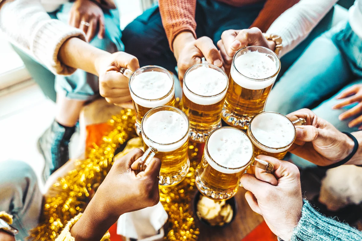 A group of friends raising frothy beer mugs together, surrounded by festive decorations