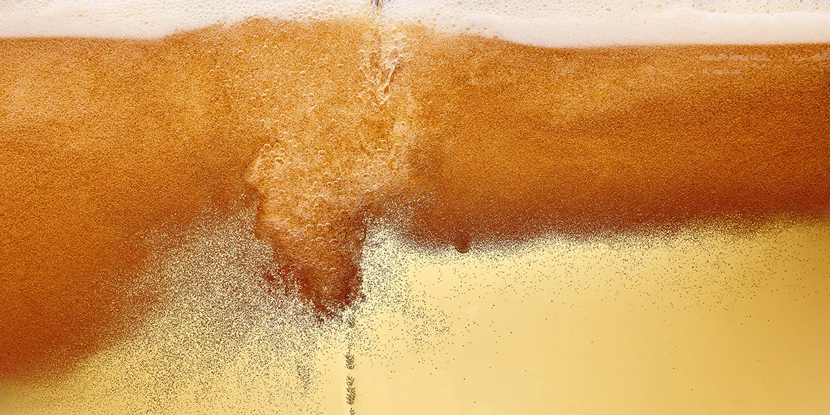 Close-up of golden beer being poured with a frothy head, highlighting January drinks deals near you at Wine Rack